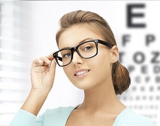 Young woman face in eyeglasses with eye chart - eye care in Medford, OR Young woman face in eyeglasses with eye chart - eye care in Medford, OR