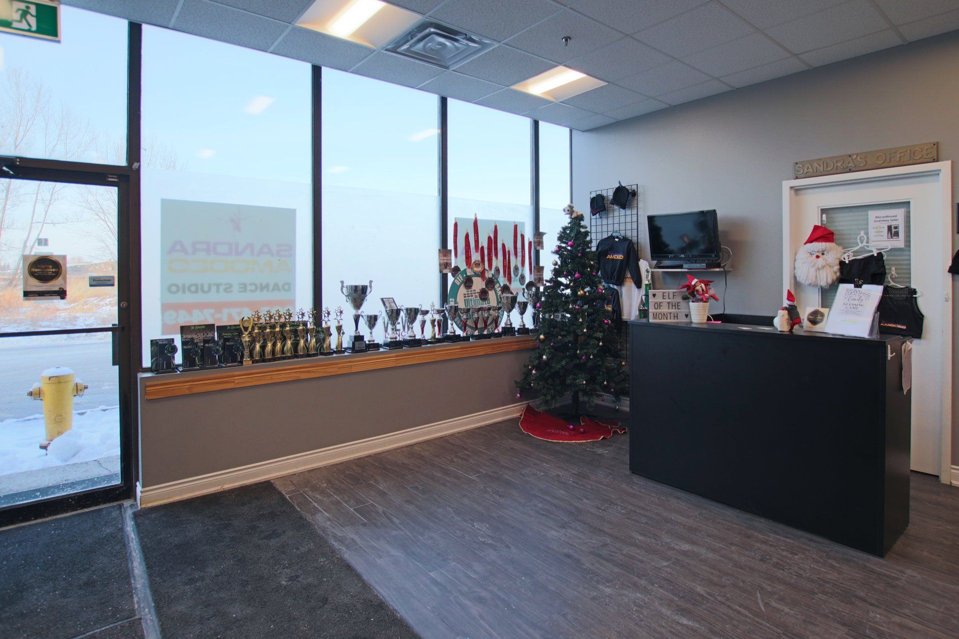 Lobby with a black reception desk, Christmas tree, awards display, and large windows.