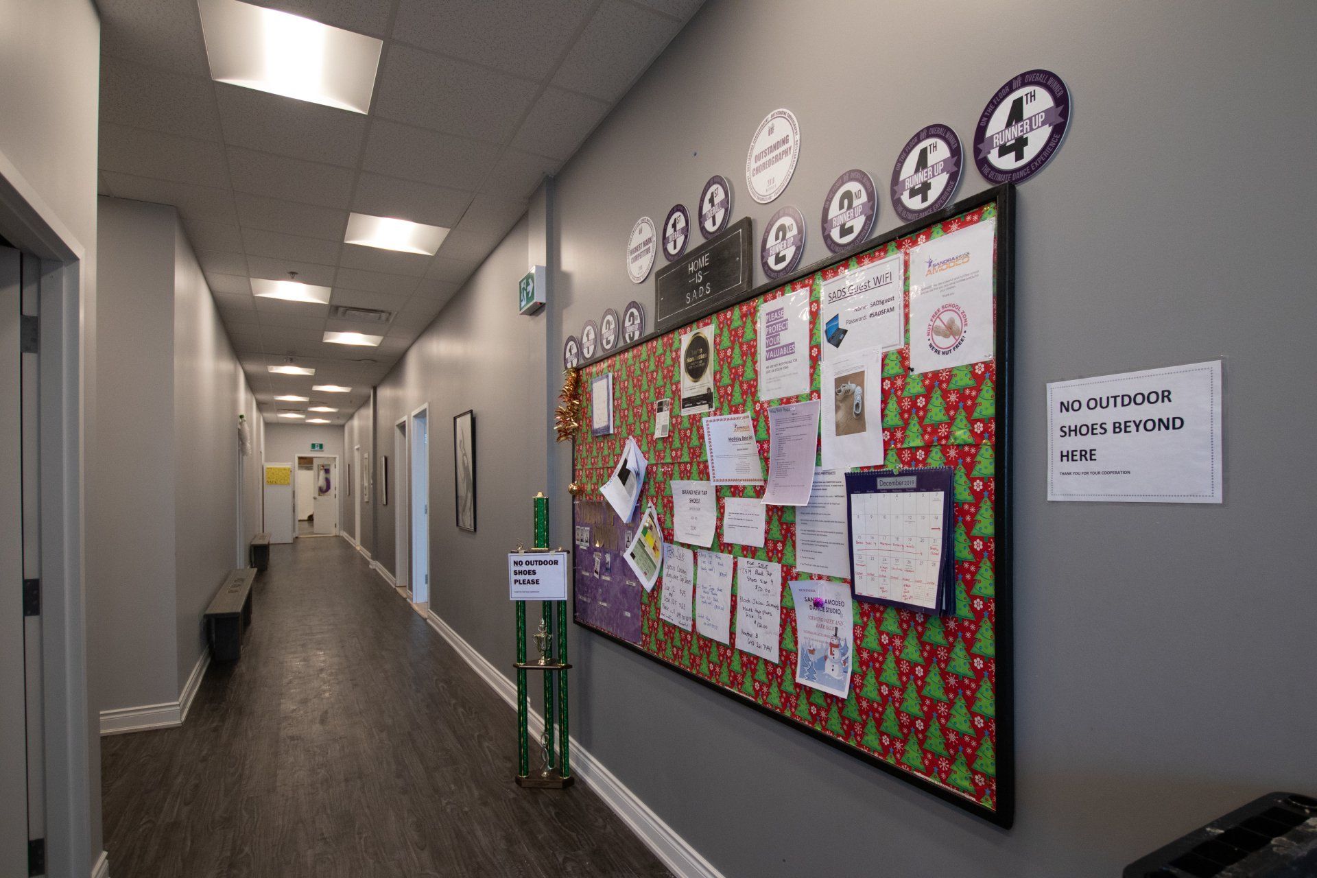 Office hallway with bulletin boards, wall clocks, and fluorescent ceiling lights