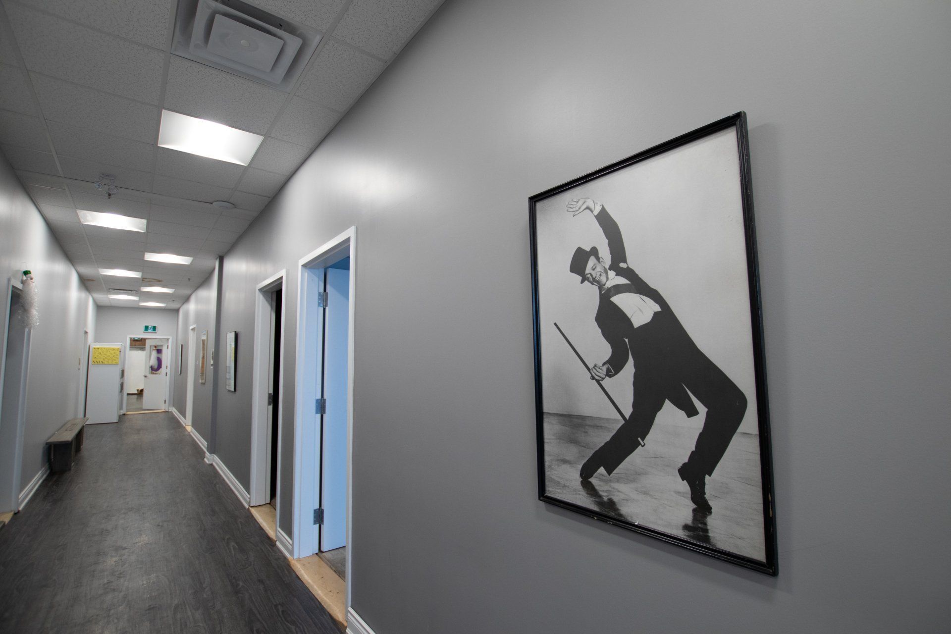 Bright hallway with blue doors and a framed black-and-white dancer silhouette on the wall.