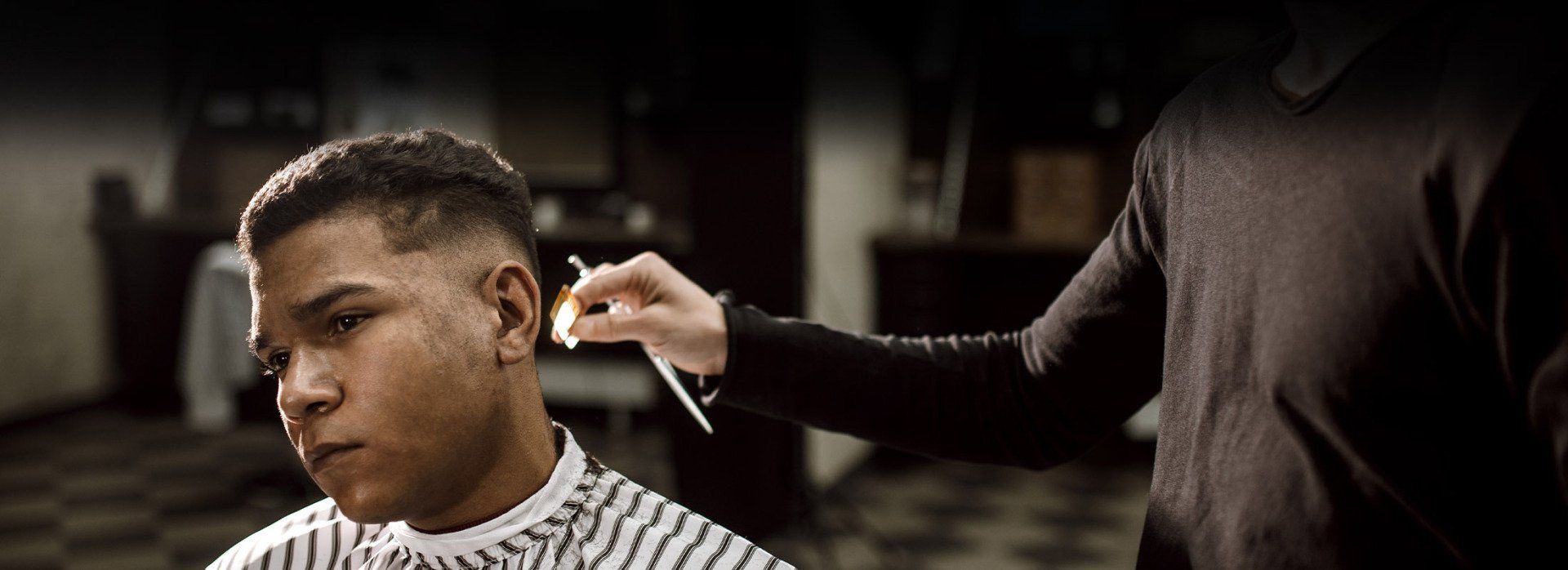 A man is getting his hair cut by a barber in a barber shop.