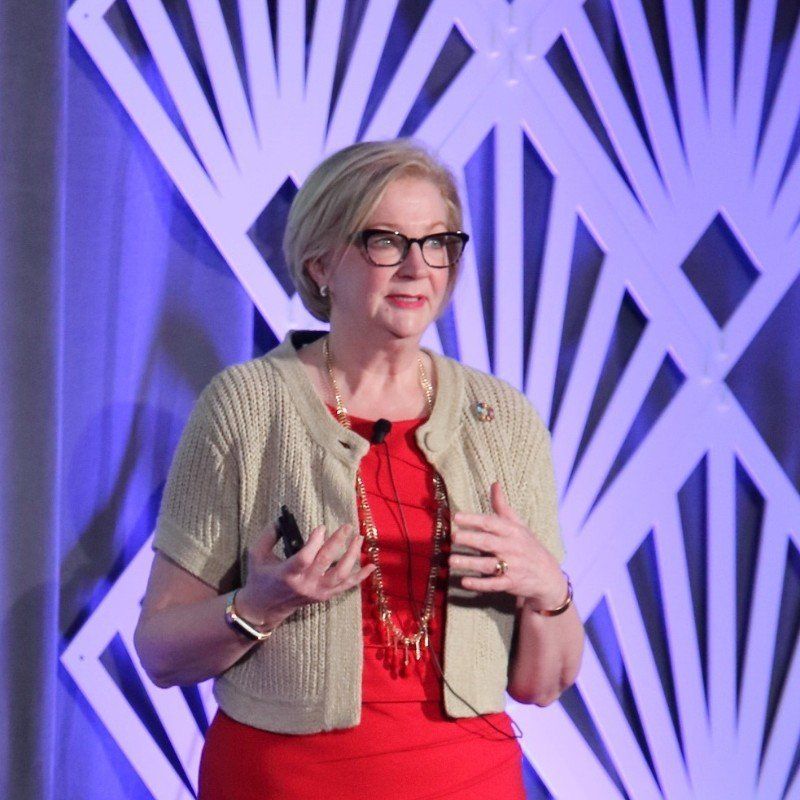 A woman wearing glasses and a red dress is giving a presentation
