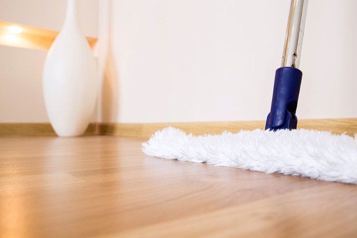 A person is cleaning a wooden floor with a mop.