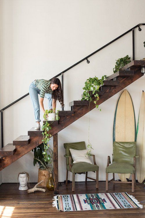 woman on steps reaching down to adjust plant