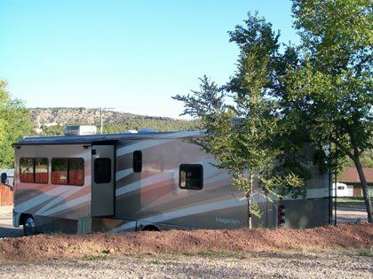 A rv parked in a gravel area with trees in the background