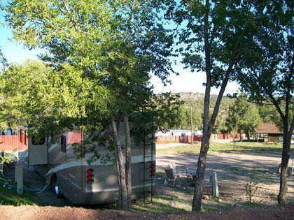 A rv is parked in a campground surrounded by trees