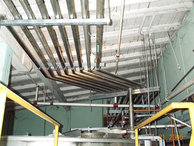 A bunch of pipes are hanging from the ceiling of a building