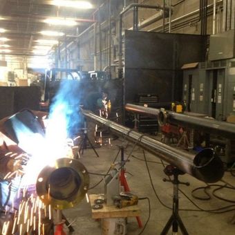 A man is welding a pipe in a factory
