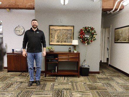 A man is standing in a room with a wreath on the wall.
