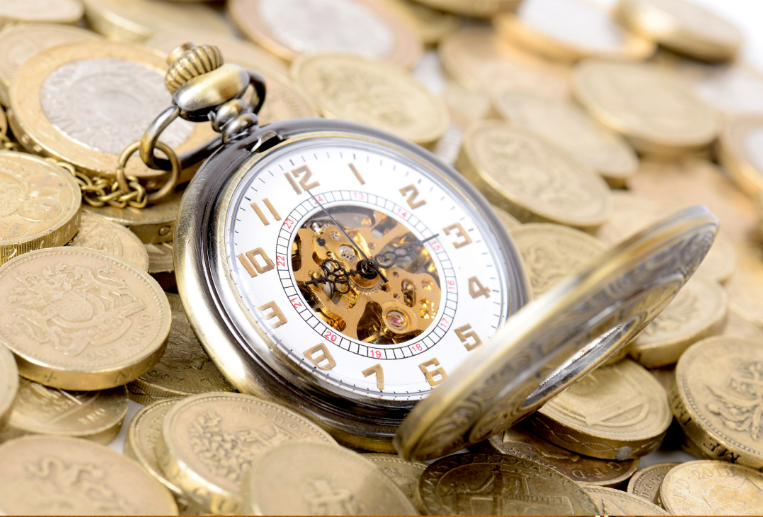 A gold pocket watch resting on a pile of gold coins