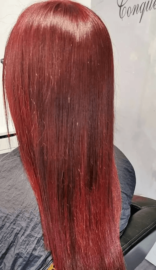 A woman with long red hair is sitting in a chair.