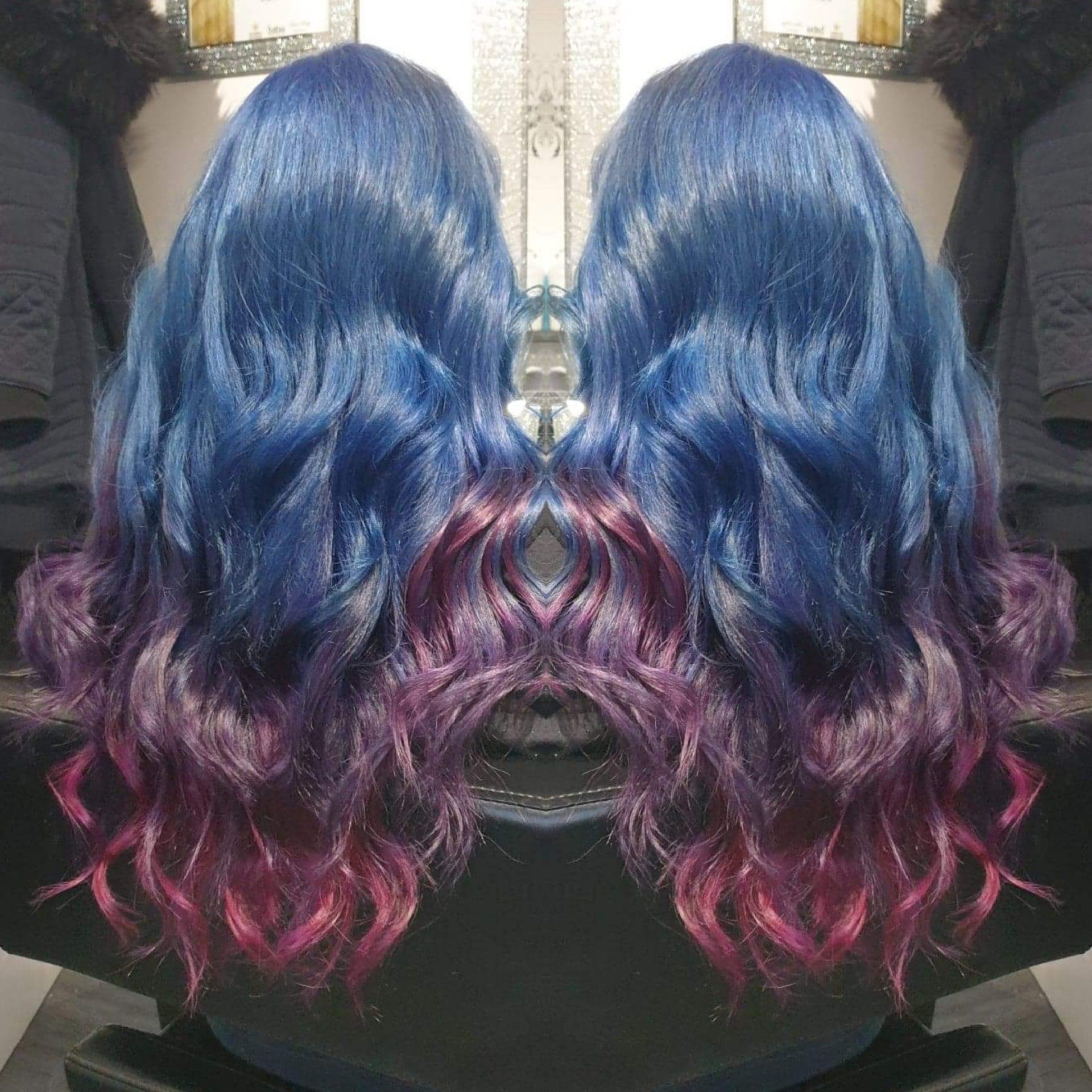 A woman with blue and purple hair is sitting in a chair.