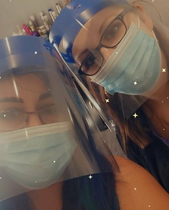 Two women wearing face masks and face shields