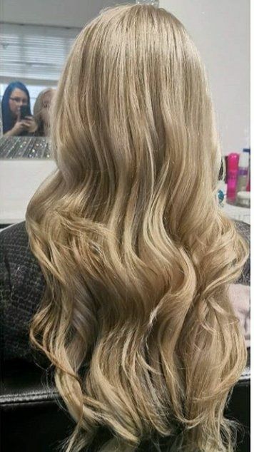 A woman with long blonde hair is sitting in front of a mirror.