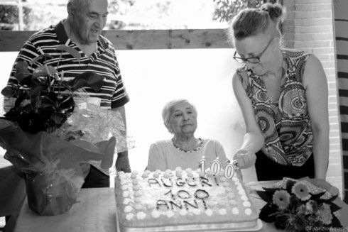 assistente di una casa di riposo accende le candele di una torta di compleanno