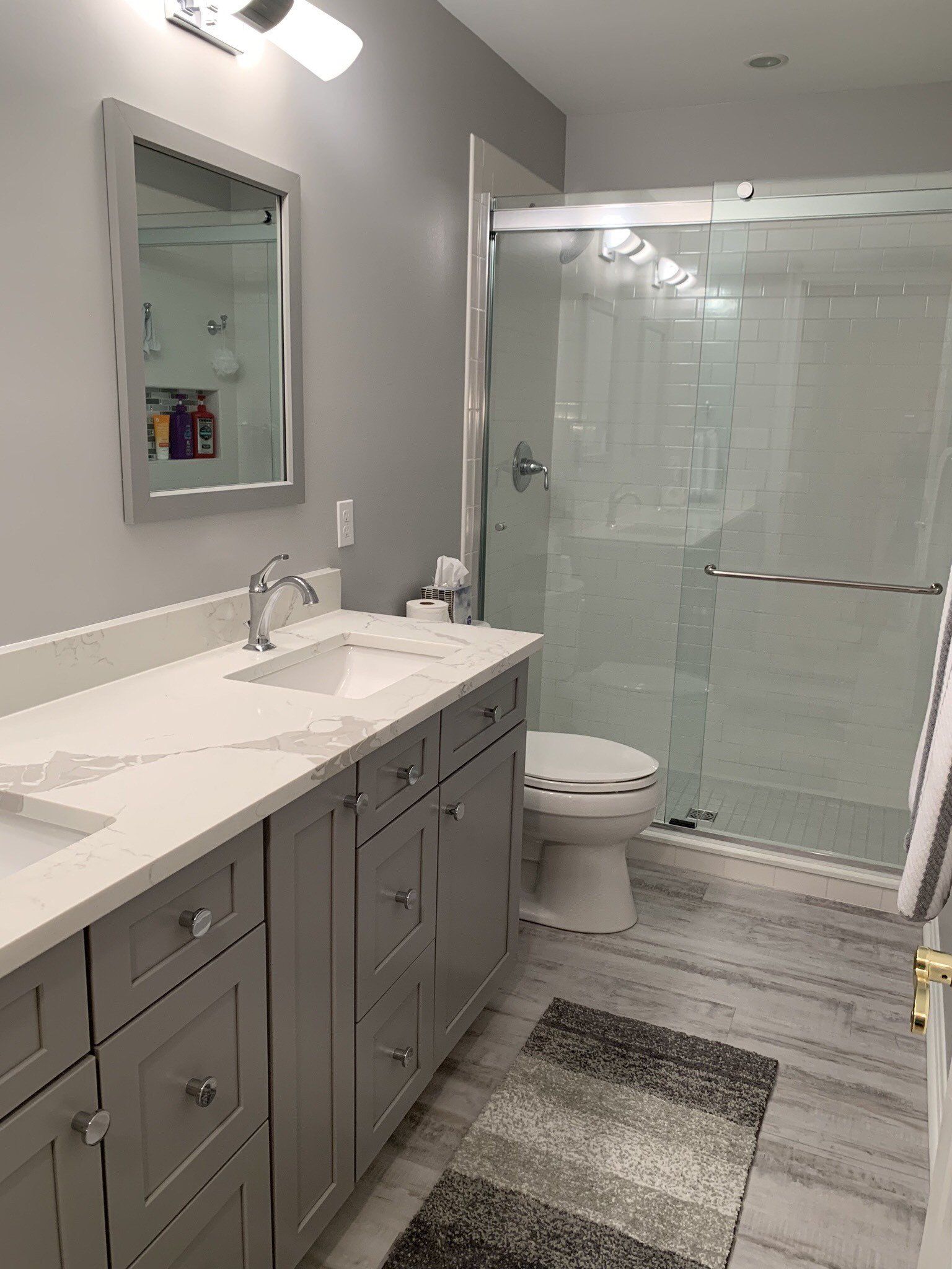 A bathroom with a sink , toilet , shower and mirror.