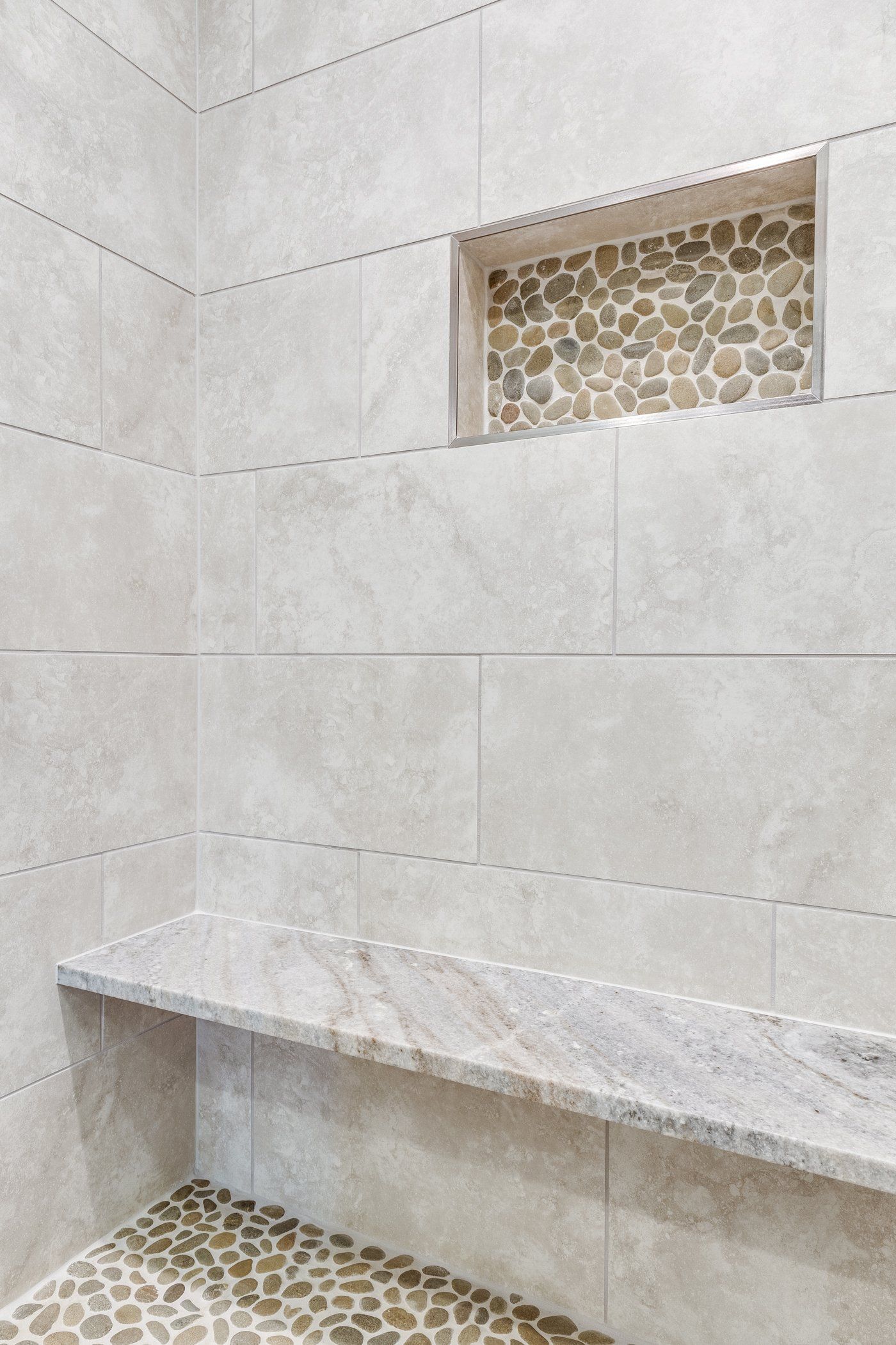 A shower with a bench and a niche in the wall.