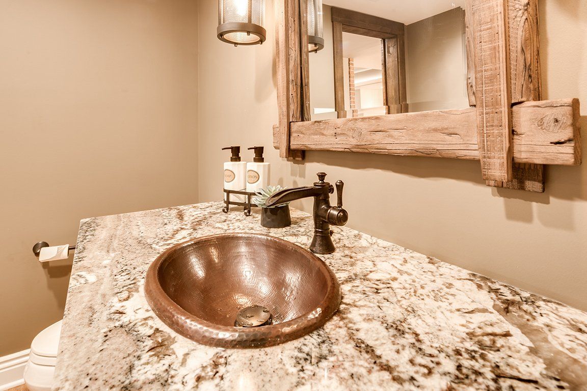 A bathroom with a copper sink and a wooden mirror.