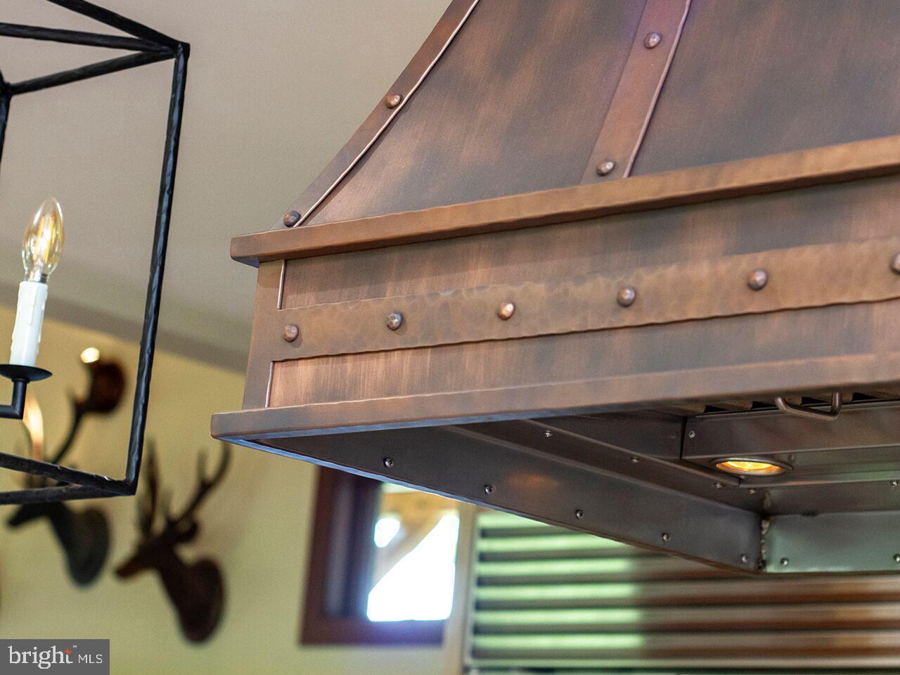 A copper hood is hanging from the ceiling in a kitchen
