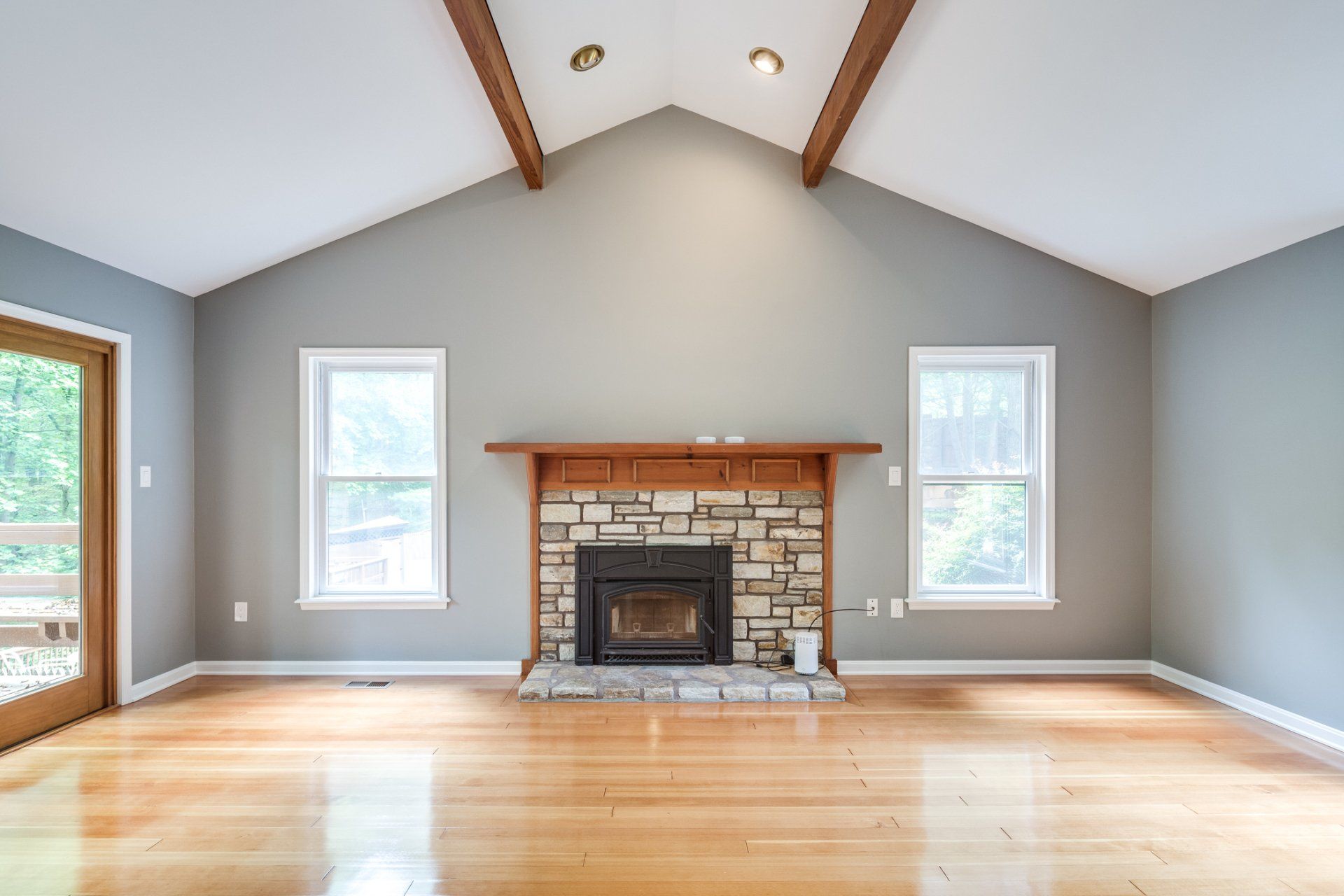 An empty living room with a fireplace and a vaulted ceiling.