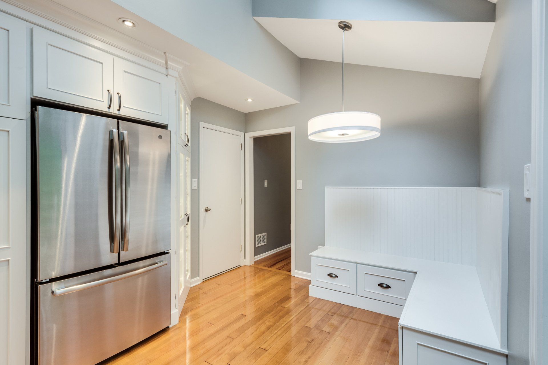 A kitchen with a stainless steel refrigerator and a bench.