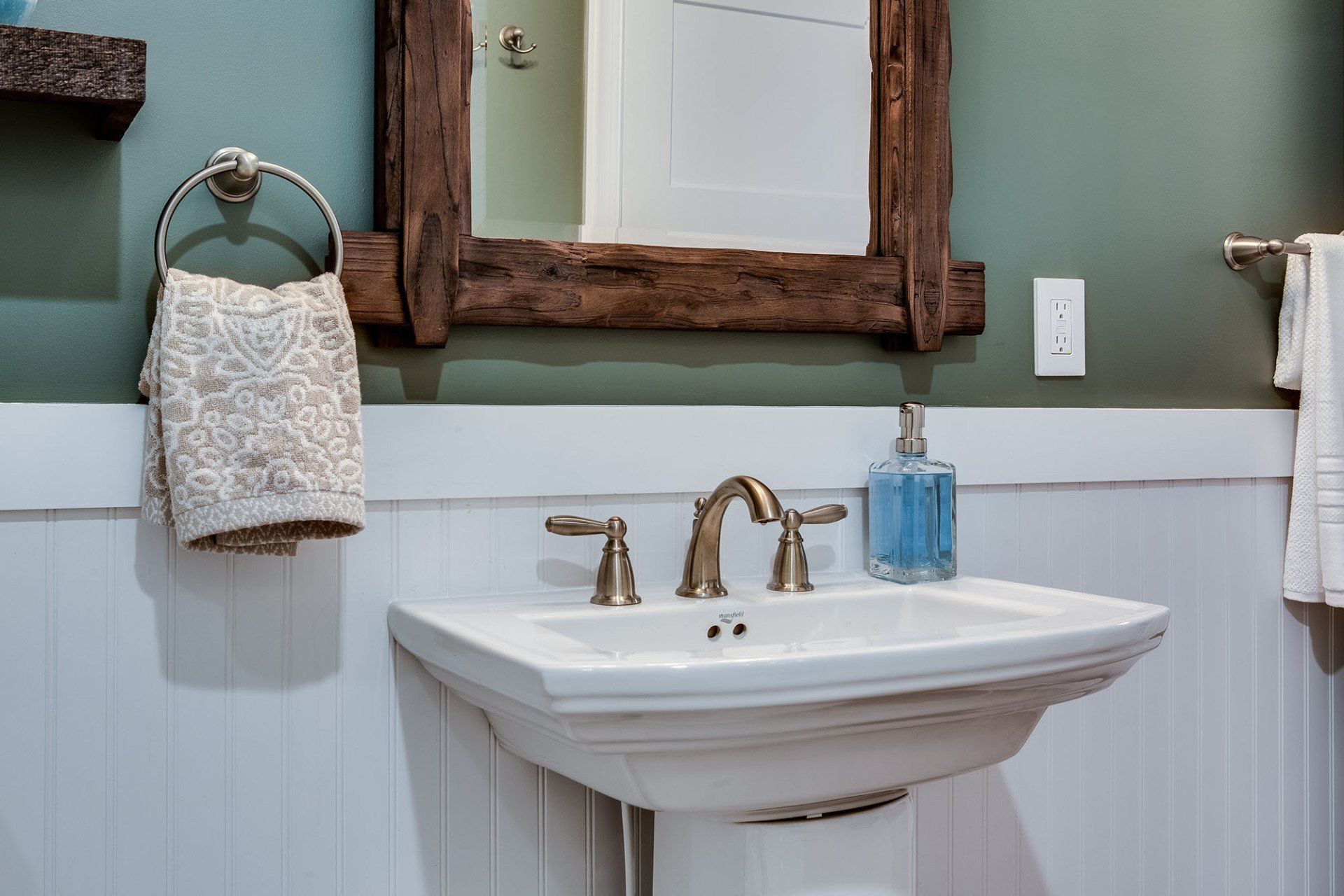 A bathroom with a sink , mirror and towels