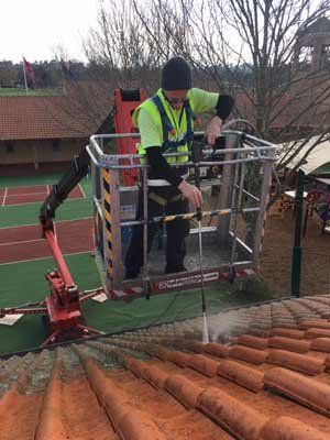 man pressure washing roof