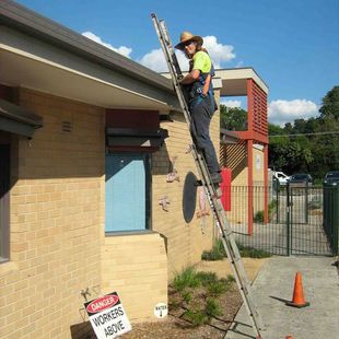 man on ladder cleaning gutters