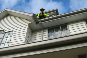 man on roof of house cleaning gutters