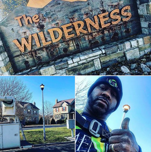 A man is giving a thumbs up in front of a sign that says the wilderness