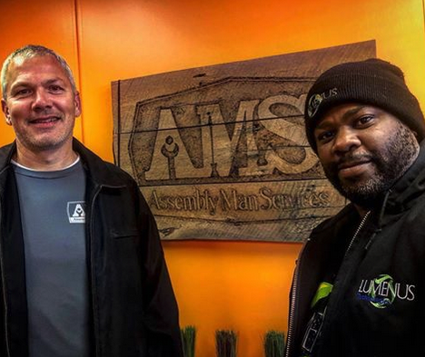 Two men standing in front of a sign that says arms
