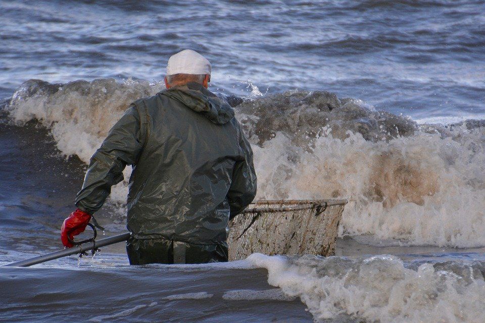 pixabay, lizenzfrei Ein Mann fischt mit einem Eimer im Meer.