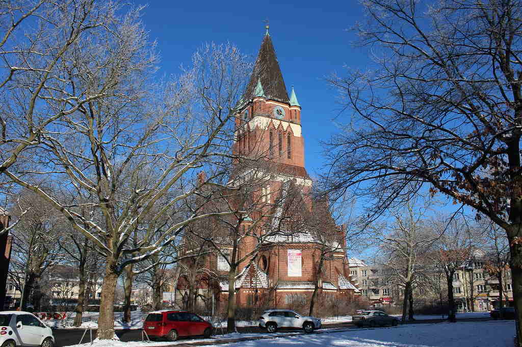 eigen Aufnahme 2021, lizenzfrei Ein großes Backsteingebäude mit einem Kirchturm ist von schneebedeckten Bäumen umgeben.