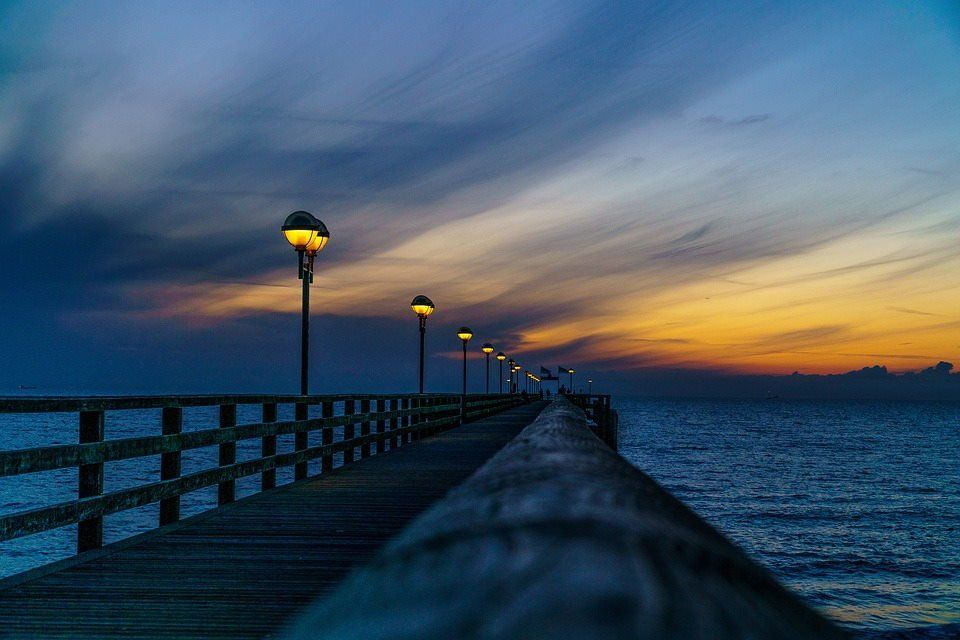 pixabay, lizenzfrei Ein Pier mit Blick auf das Meer bei Sonnenuntergang und einer Reihe von Straßenlaternen.