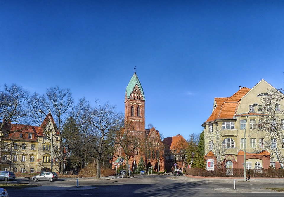 pixabay, lizenzfrei Ein großes Backsteingebäude mit Gründach ist von anderen Gebäuden umgeben.