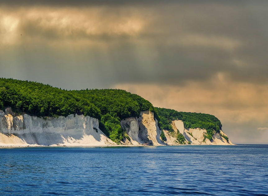 Ein großes Gewässer mit einer Klippe im Hintergrund.