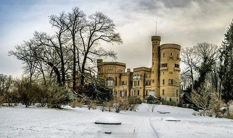 pixabay, lizenzfrei Ein großes Schloss ist von Schnee und Bäumen umgeben.