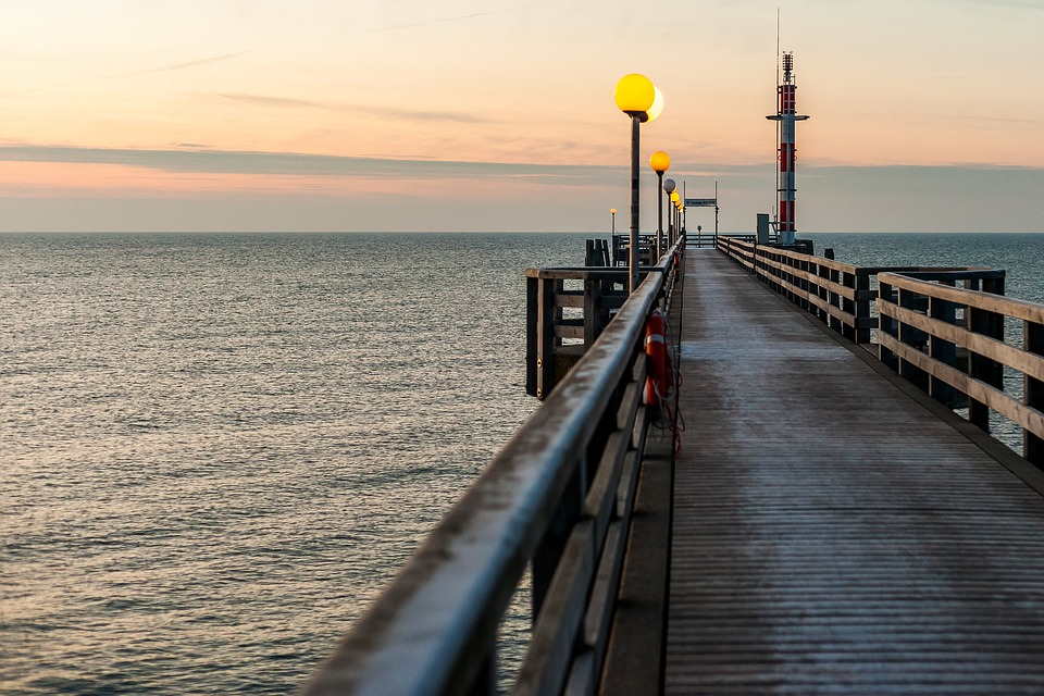 pixabay, lizenzfrei Ein Holzsteg, der bei Sonnenuntergang ins Meer führt.