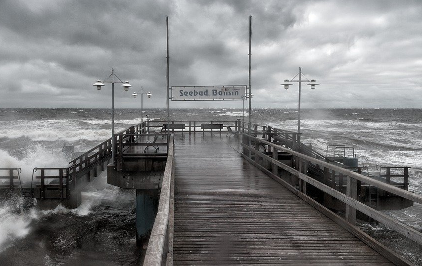 pixabay, lizenzfrei Ein Schwarzweißfoto eines Piers, gegen den Wellen schlagen.