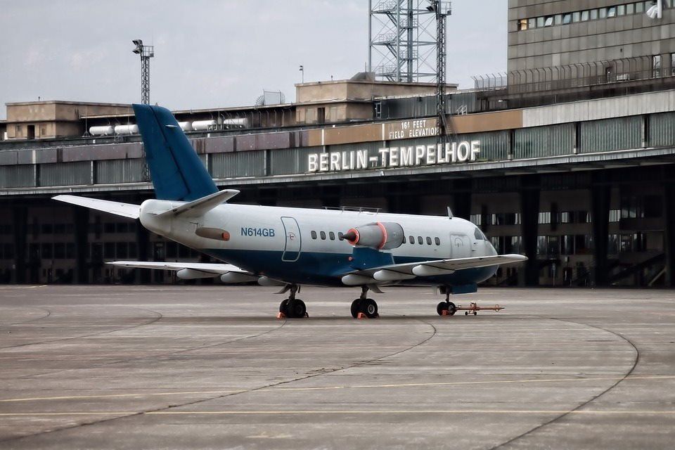 pixabay, lizenzfrei Ein blau-weißes Flugzeug steht vor einem Gebäude mit der Aufschrift „Berlin-Tempelhof“