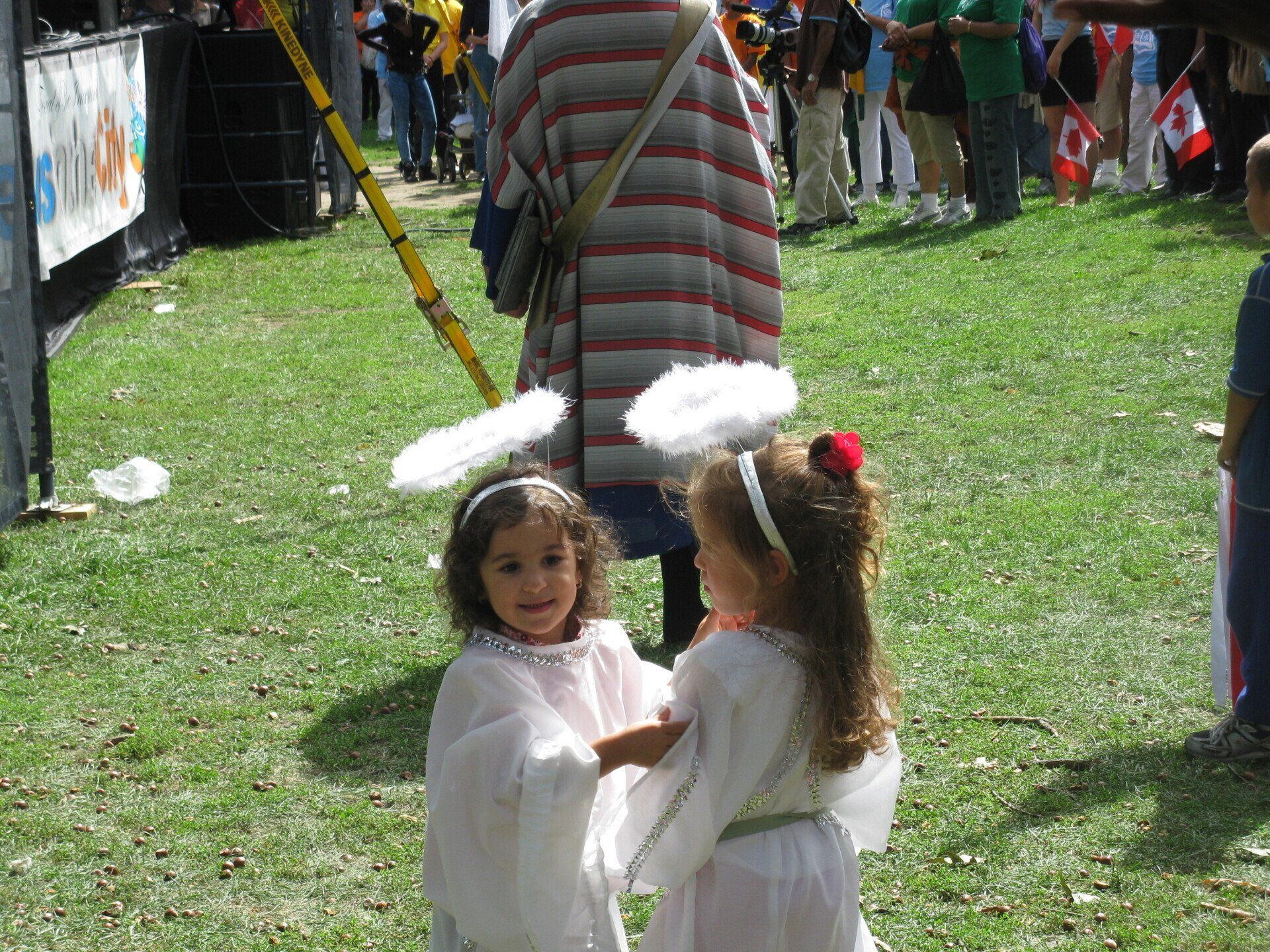 Two little girls dressed as angels are standing in the grass
