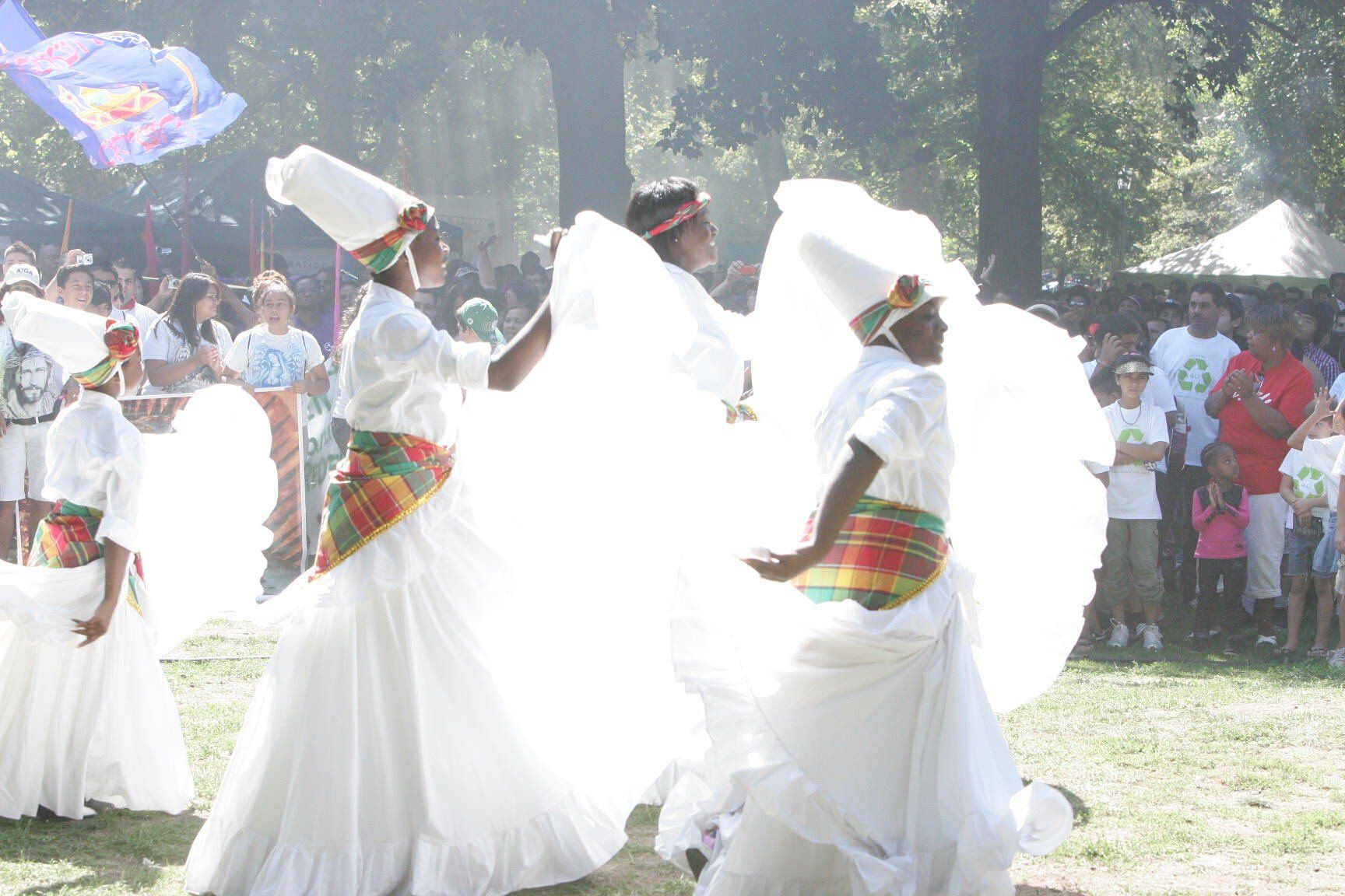A group of people in white dresses are dancing in front of a crowd.