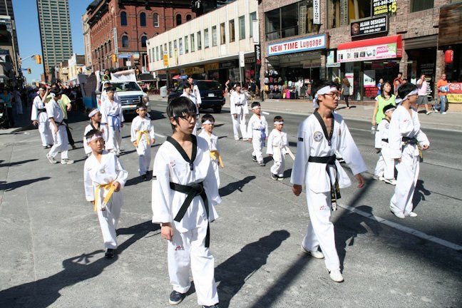 A group of people in martial arts uniforms march down a street