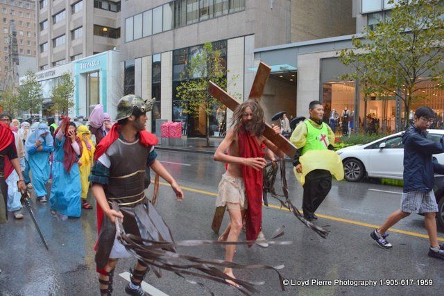 A group of people dressed as jesus carrying a cross down a street.