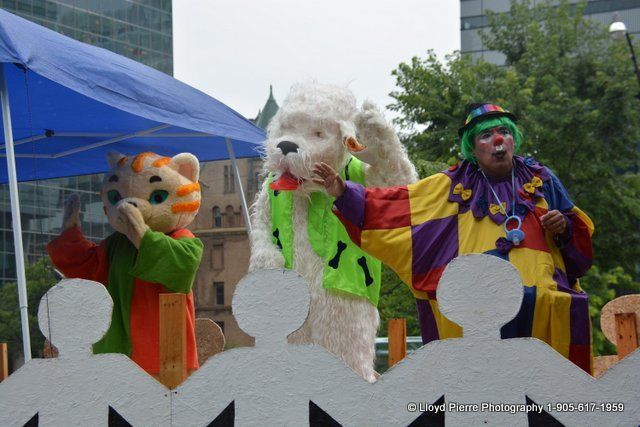A group of clowns and mascots are standing in front of a blue tent