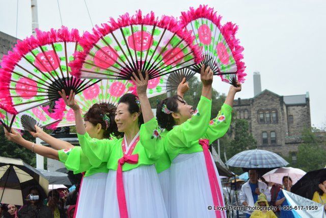 A group of women in traditional korean costumes are holding fans in the air