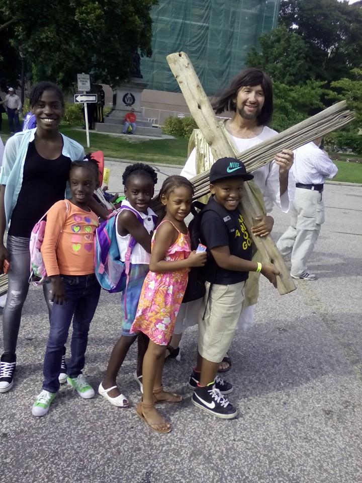 A group of children are posing for a picture with a man dressed as jesus