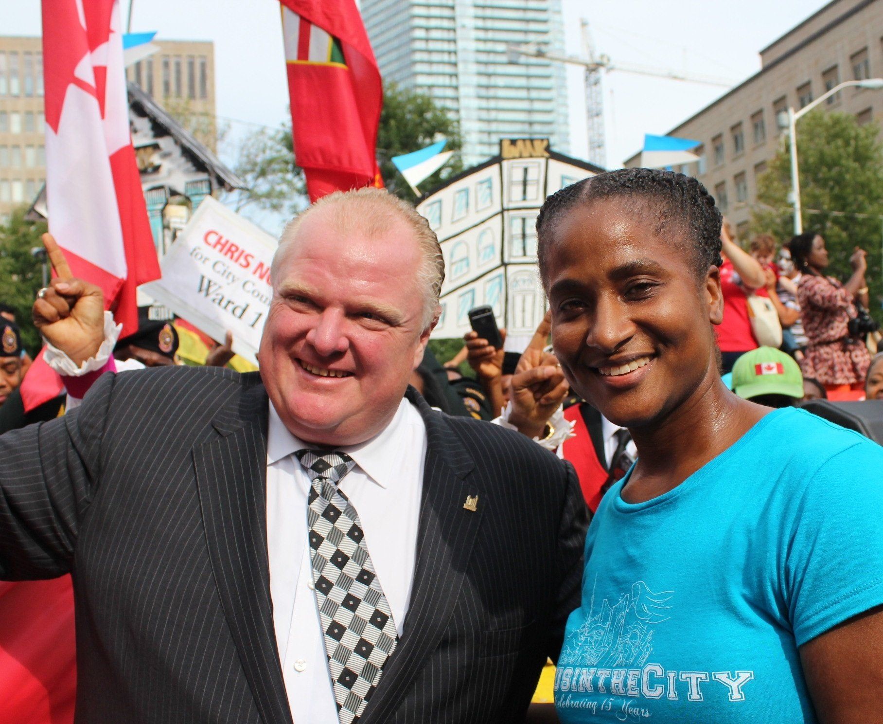 A man in a suit and tie poses with a woman in a blue shirt that says city