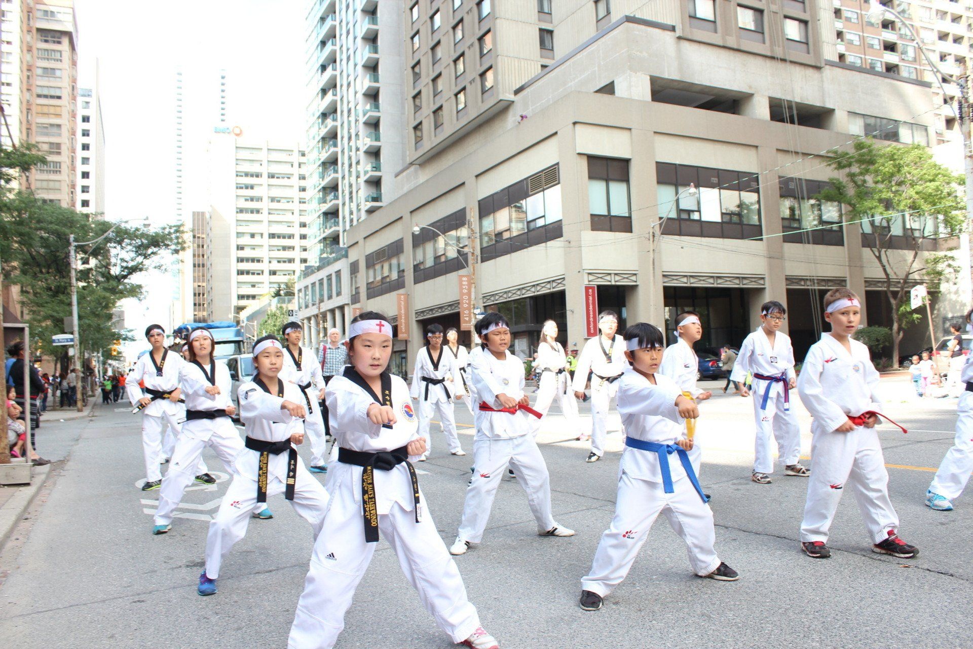 A group of people are practicing martial arts on a city street.