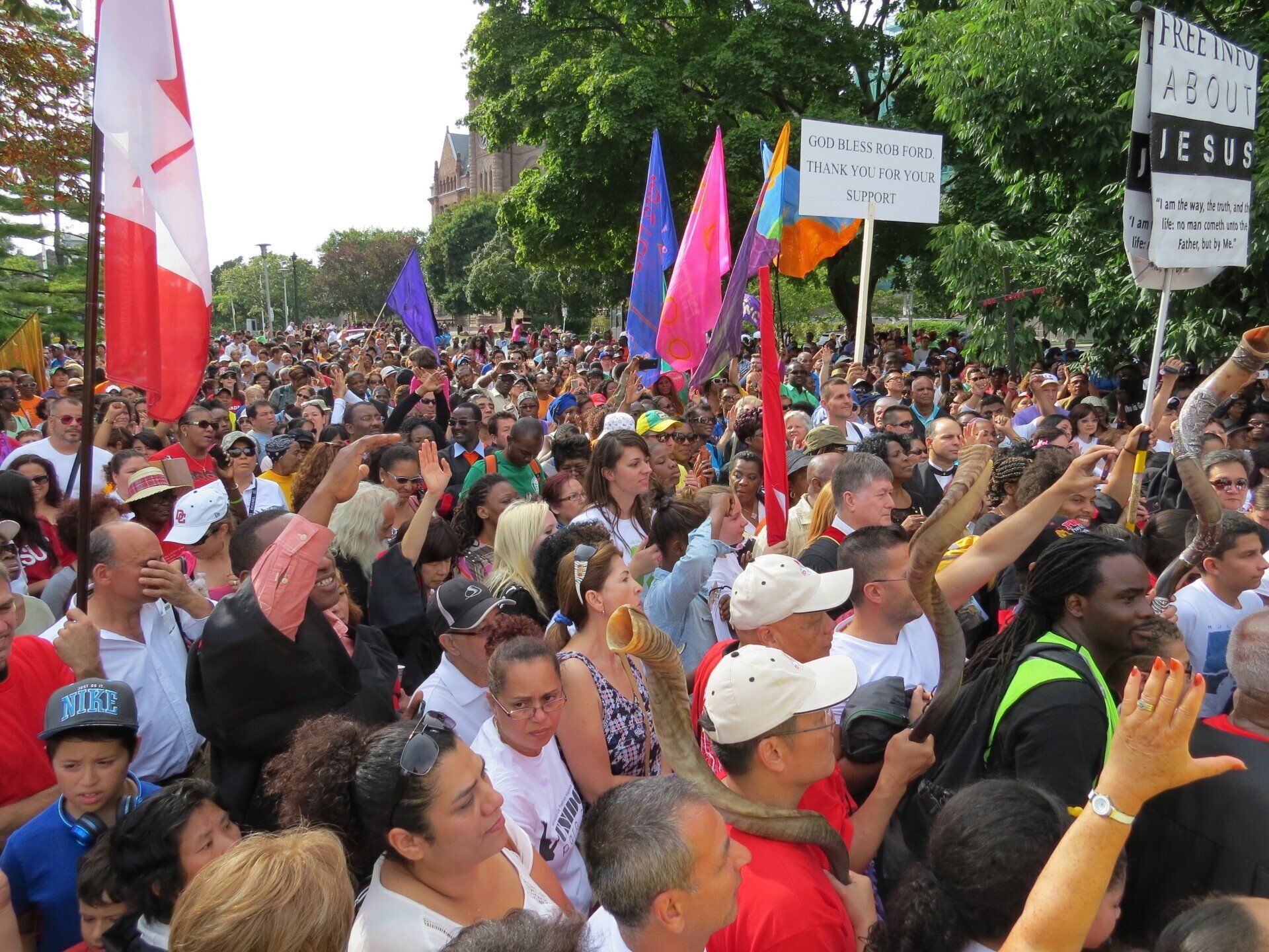 A crowd of people are gathered on a street holding flags and signs.
